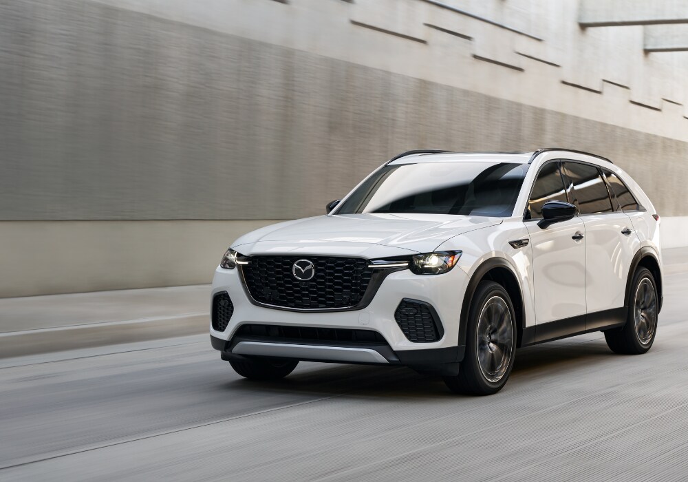mazda-cx-70-for-sale.png 2025 Mazda CX-70 driving down a paved road towards the camera