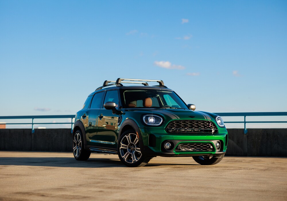 2025-mini-cooper-countryman.png Green MINI Cooper Countryman for sale parked on the top of a parking deck. There is a blue sky in the background