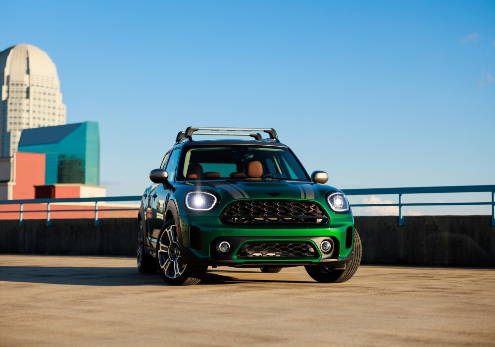 2025-mini-countryman-for-sale.png Green 2025 MINI Countryman parked on the top level of a parking deck. There are tall buildings in the background