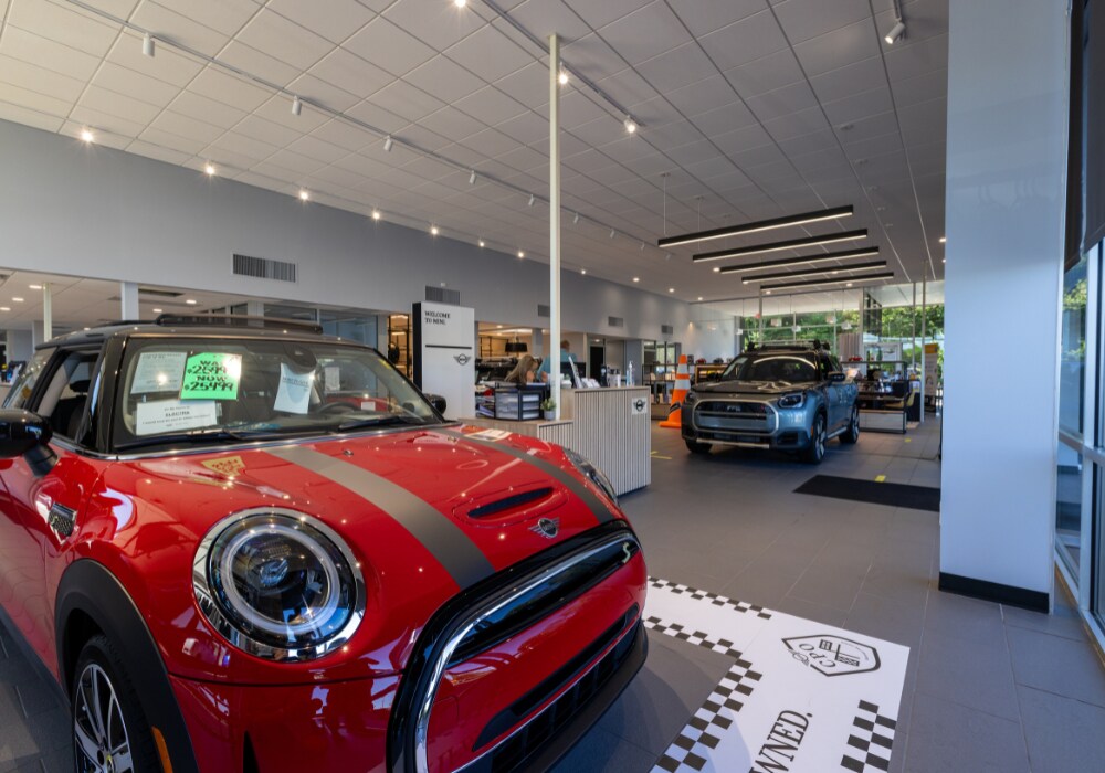 new-mini-cars-for-sale-in-winston-salem.png Interior of the Flow MINI dealership in Winston-Salem. There are two Mini Cooper cars parked inside the showroom