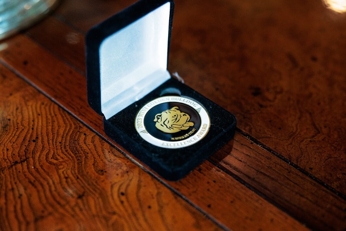 flow-mini-bulldog-award-medal.png A medal with a bulldog's face on in it in a black velvet jewelry box. the medal represents the MINI Golden Bulldog award presented to Flow MINI in Winston Salem NC in 2023