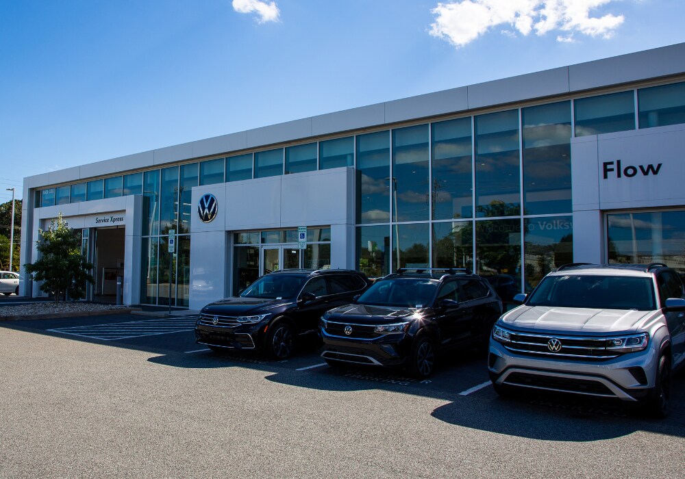 volkswagen-greensboro-dealership.png Storefront of Flow Volkswagen of Greensboro dealership with three Volkswagen cars parked in front