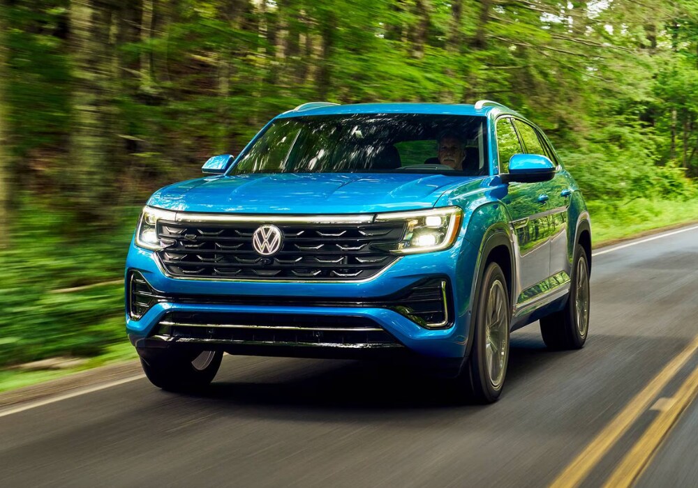 volkswagen-atlas-cross-sport-winston-salem.png Blue Volkswagen Atlas Cross sport driving down a road with trees in the background