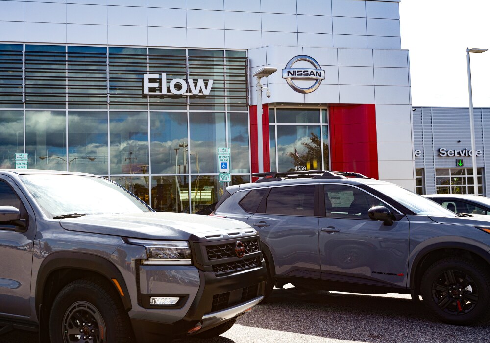 flow-nissan-fayetteville-dealership.png Two Nissan cars parked in front of the Flow Nissan of Fayetteville dealership