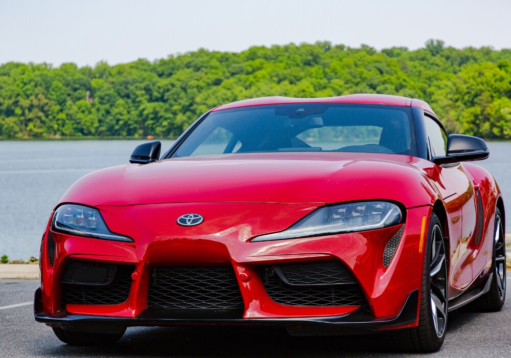 toyota-certified-pre-owned-car-for-sale-charlottesville.png Red Toyota car parked in front of a lake and trees