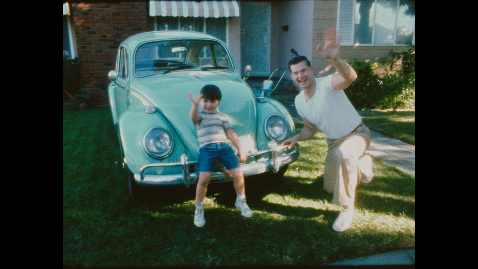 ole-VW-beetle.jpg An old photo of a father and son waving in front of a Volkswagen Beetle