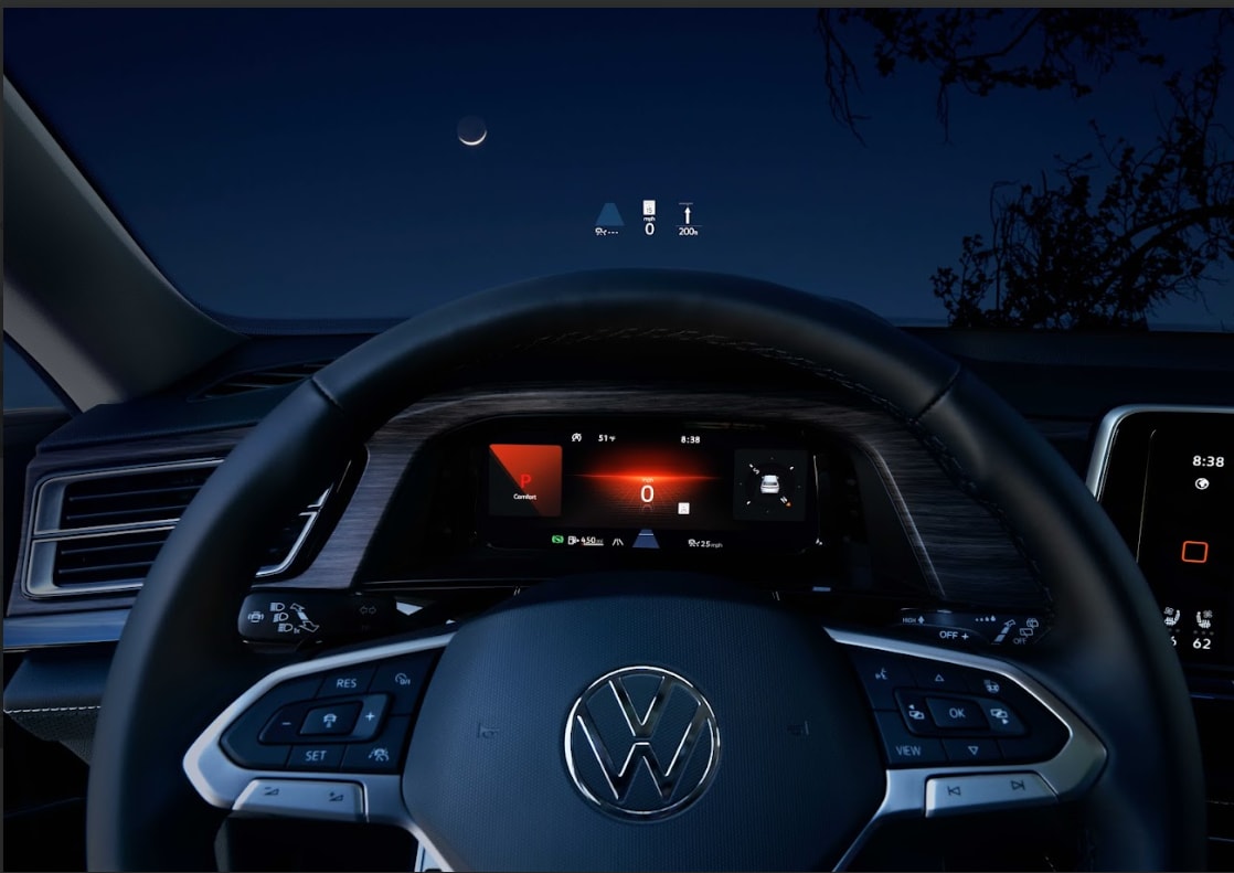 vw-vehicle-software-updates.png Steering wheel of a VW Vehicle with the dash lit up. On the front windshield, there are notifications about the car.
