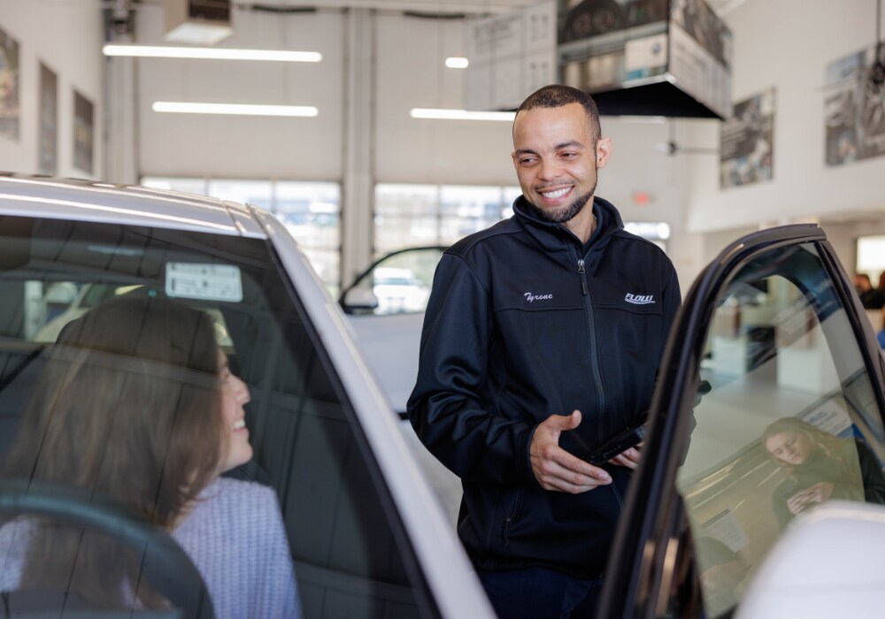 volvo-service-greensboro-nc.png A Flow service technician assisting a customer at the driver's side of her car in Greensboro