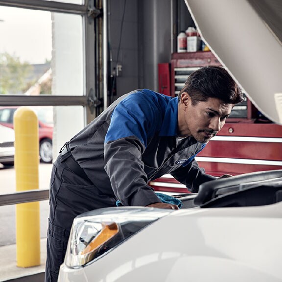 White vehicle with person inspecting under the hood