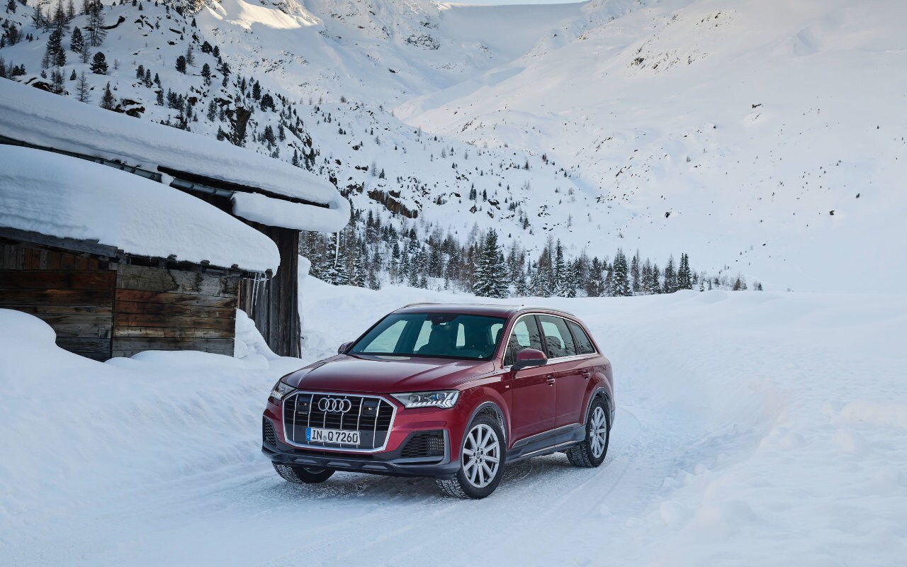 vue latérale avant d'une Audi Q7 2023 devant un chalet enneigé en montagne