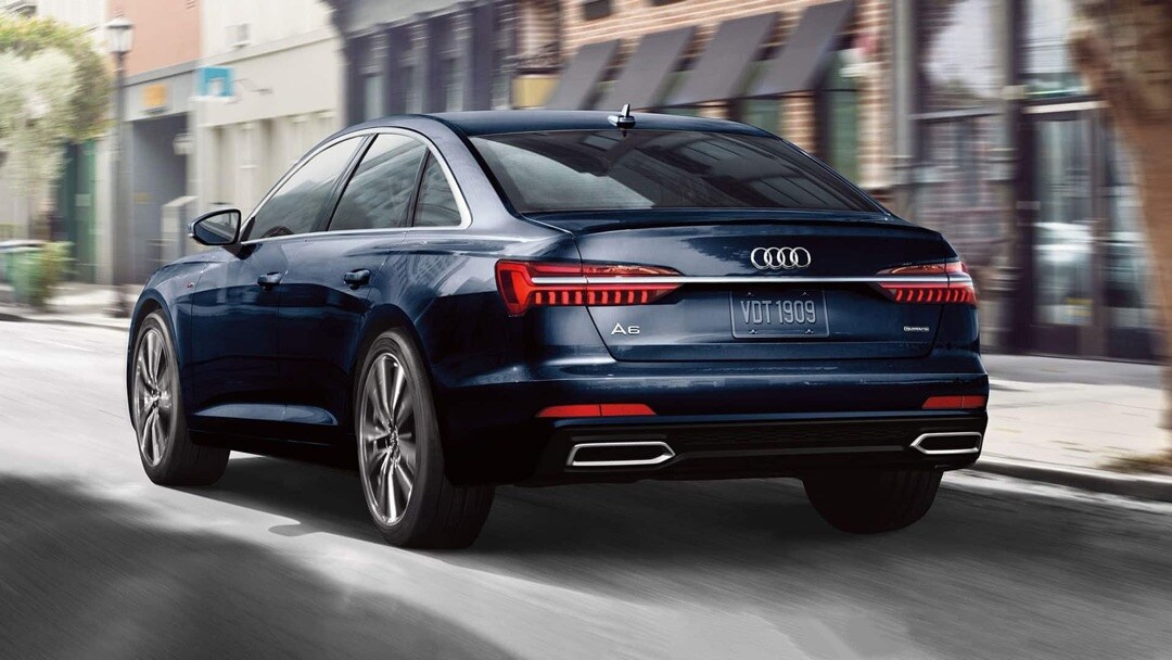 Vue 3/4 arrière de l'Audi A6 berline 2023 roulant sur une route.