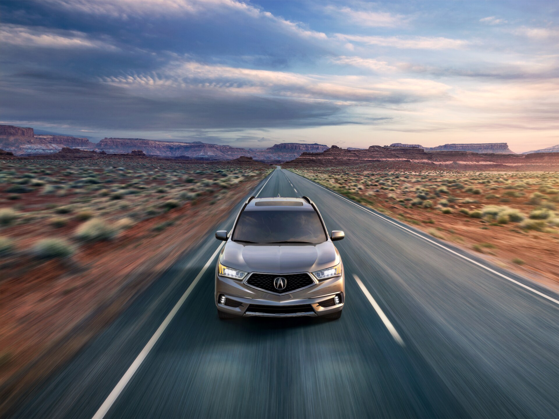 Comparison of the 2020 Acura MDX & 2020 Toyota Highlander at Acura Hunt Valley | Grey 2020 Acura MDX driving on desert road at sunset