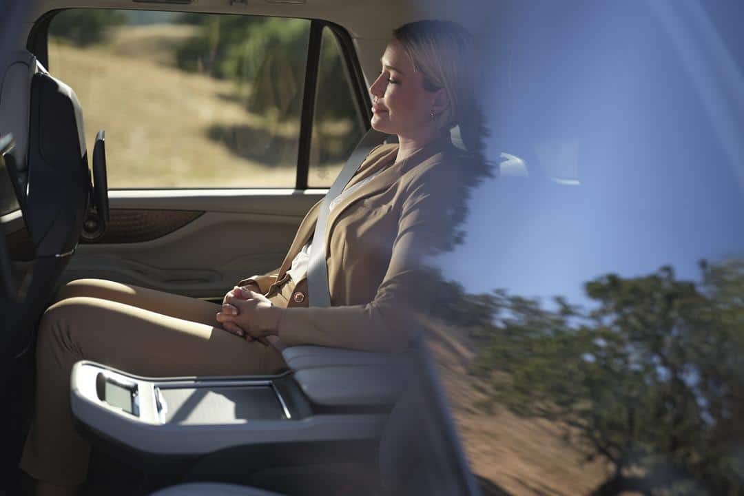 A sleek 2025 Lincoln Navigator driving on a scenic road, showcasing its presence.