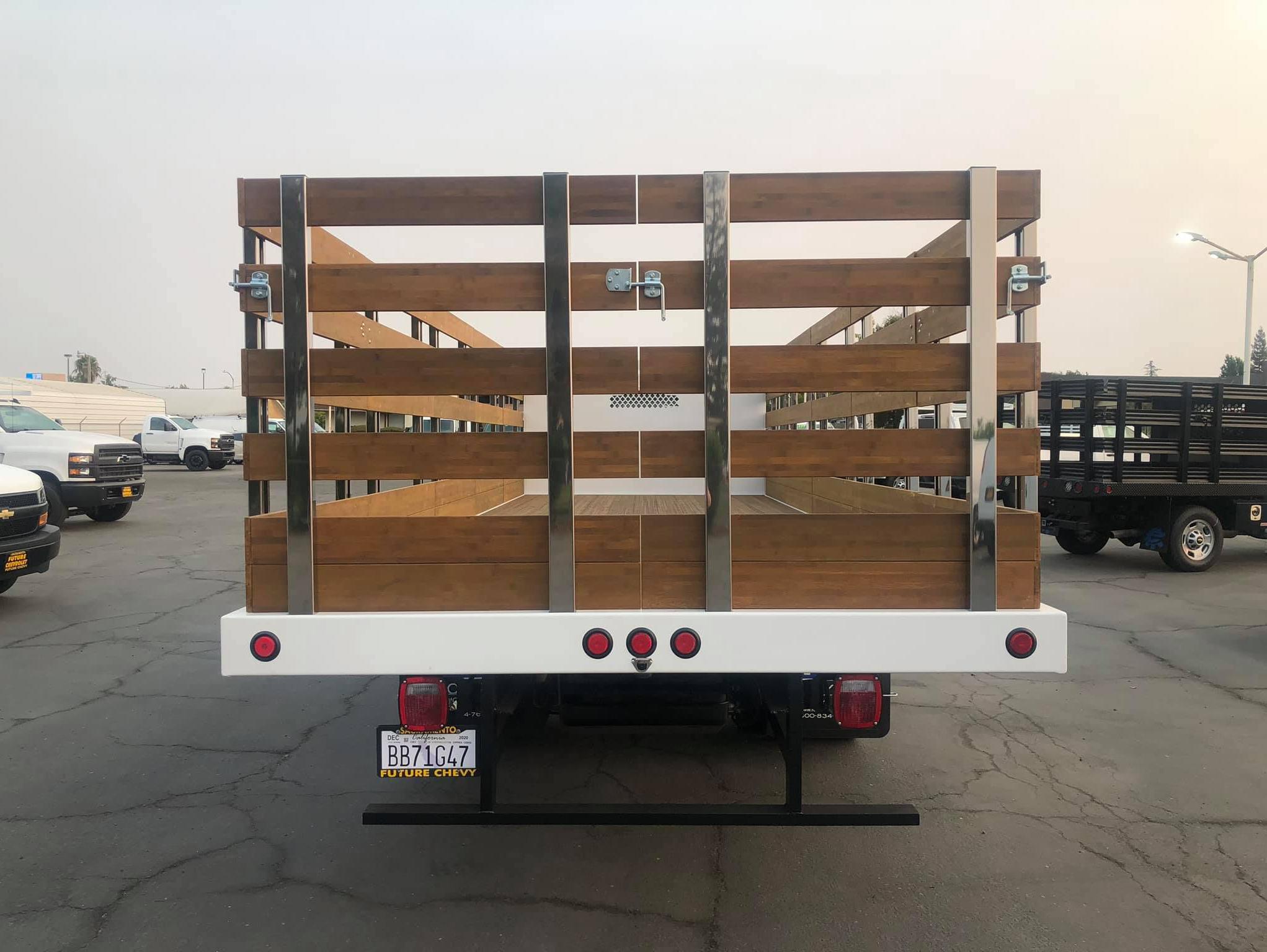 White Chevy Silverado 6500HD with 22 foot Royal Flat Bed with wooden stakes, side view