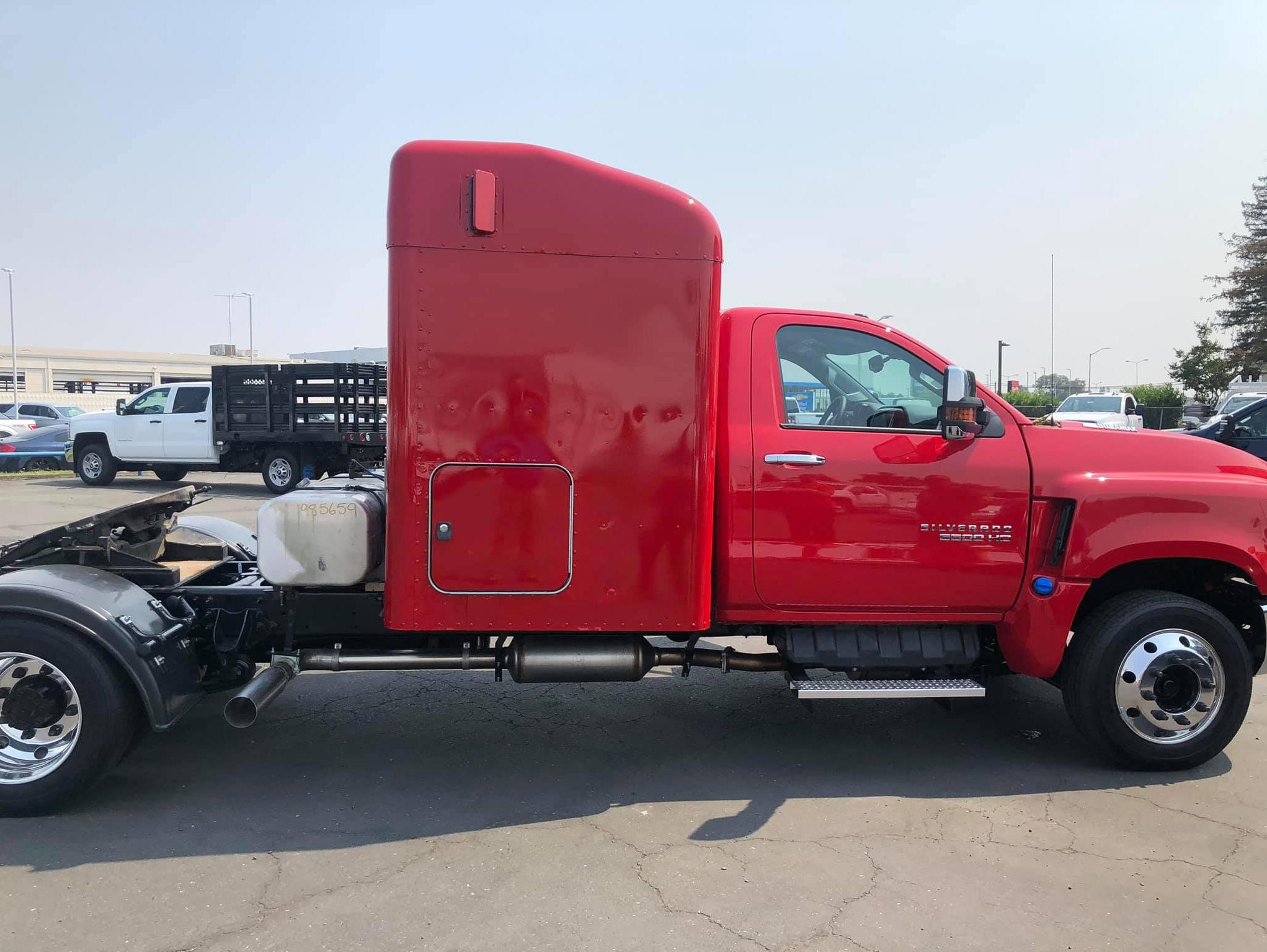 Side-view of a red Chevy Silverado 5500HD with camper and hauler body
