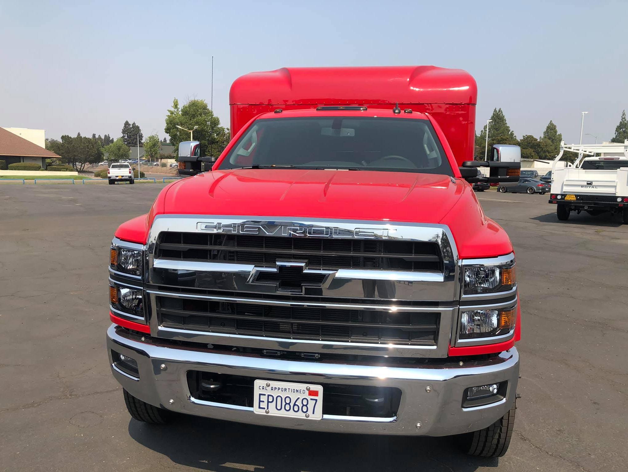 Front view of a red Chevy Silverado 5500HD with camper and hauler body