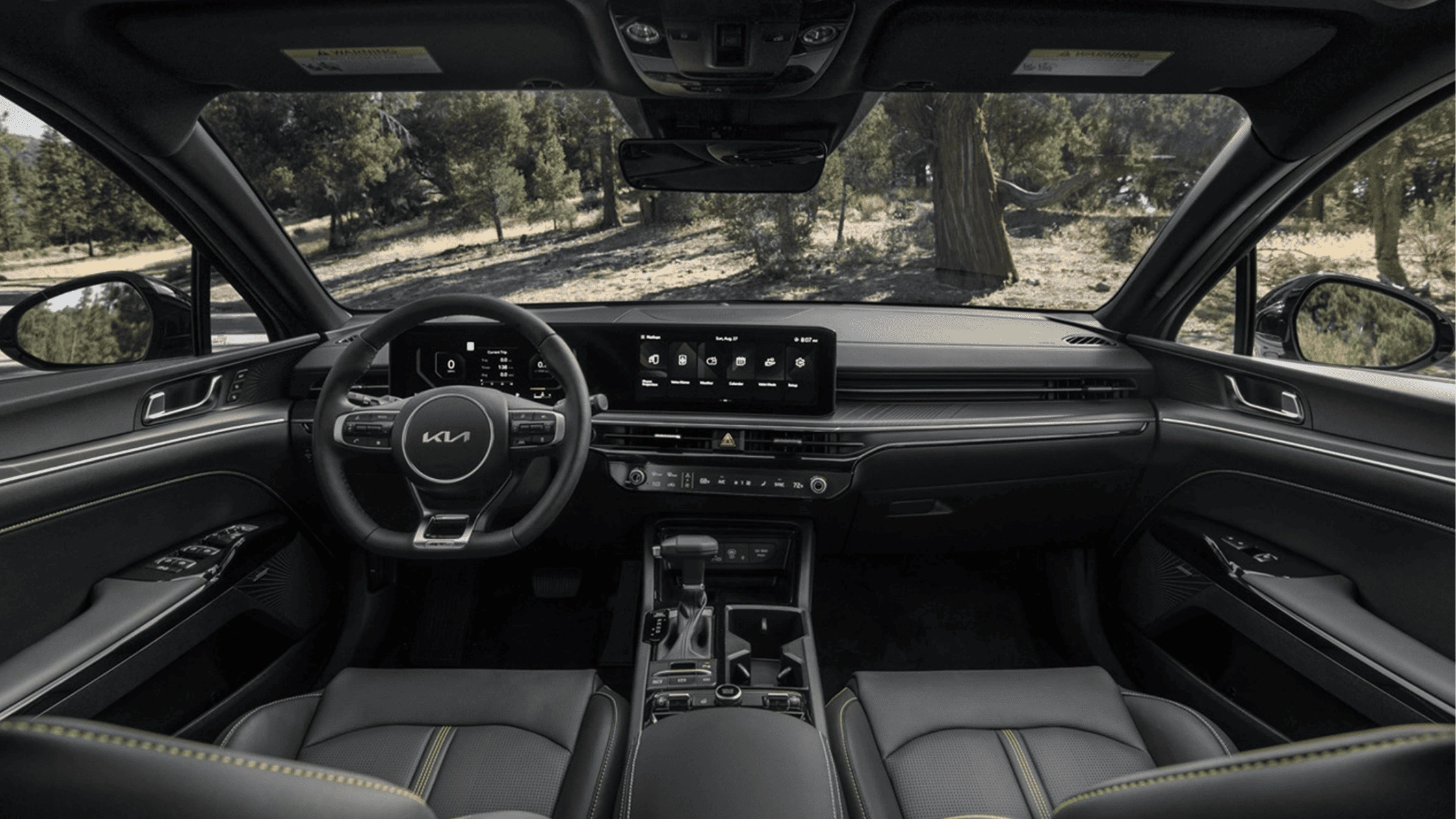 2025 Kia K5 - Safety and Driver Assistance Technologies A spacious and high-tech cockpit view of the 2025 Kia K5, highlighting a digital instrument cluster, a widescreen infotainment system, and a stylish Kia-branded steering wheel.