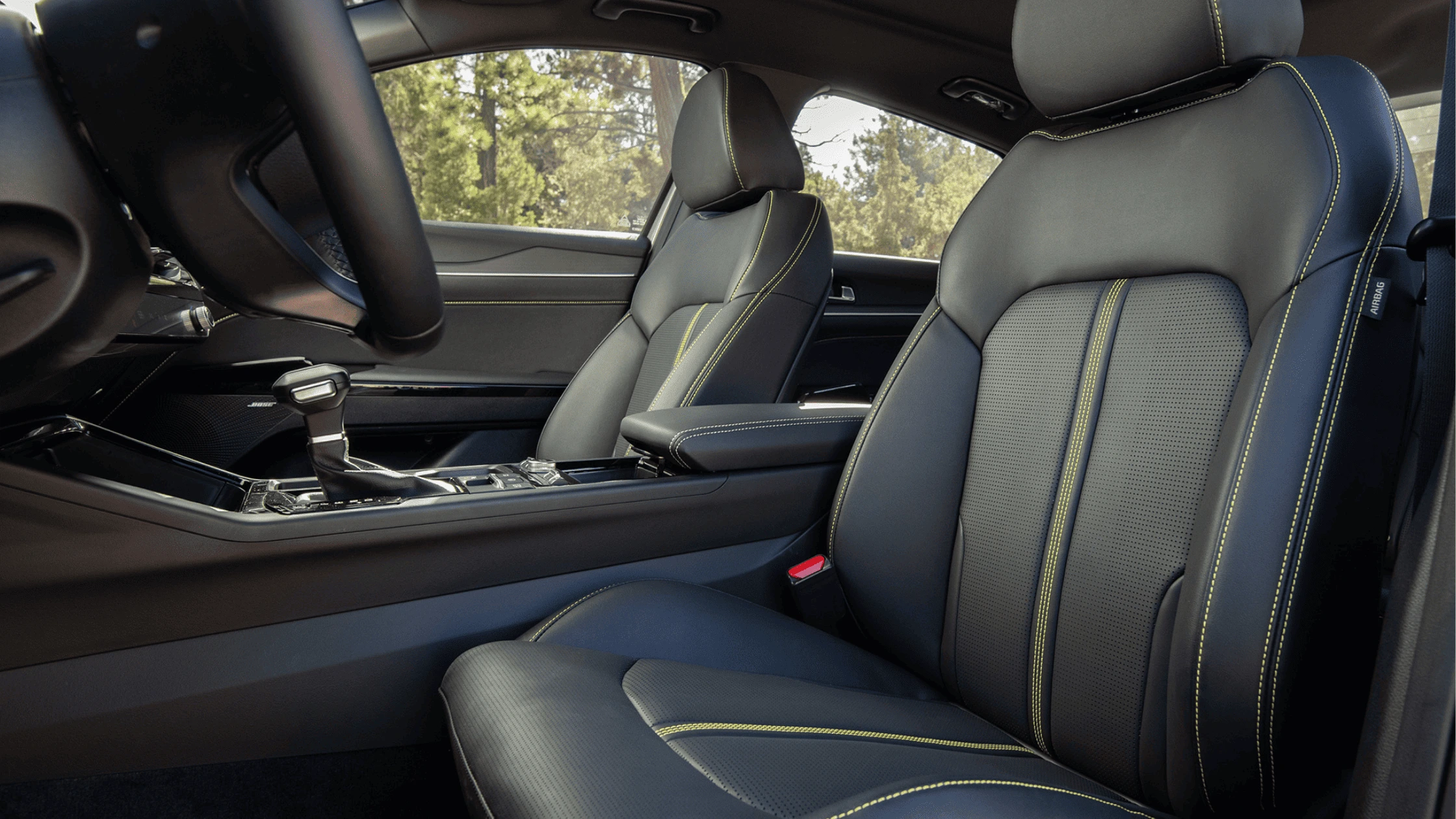 2025 Kia K5 - Interior Comfort and Technology The luxurious interior of the 2025 Kia K5, featuring black leather seats with yellow stitching, a modern center console, and a gear shift with a premium finish.