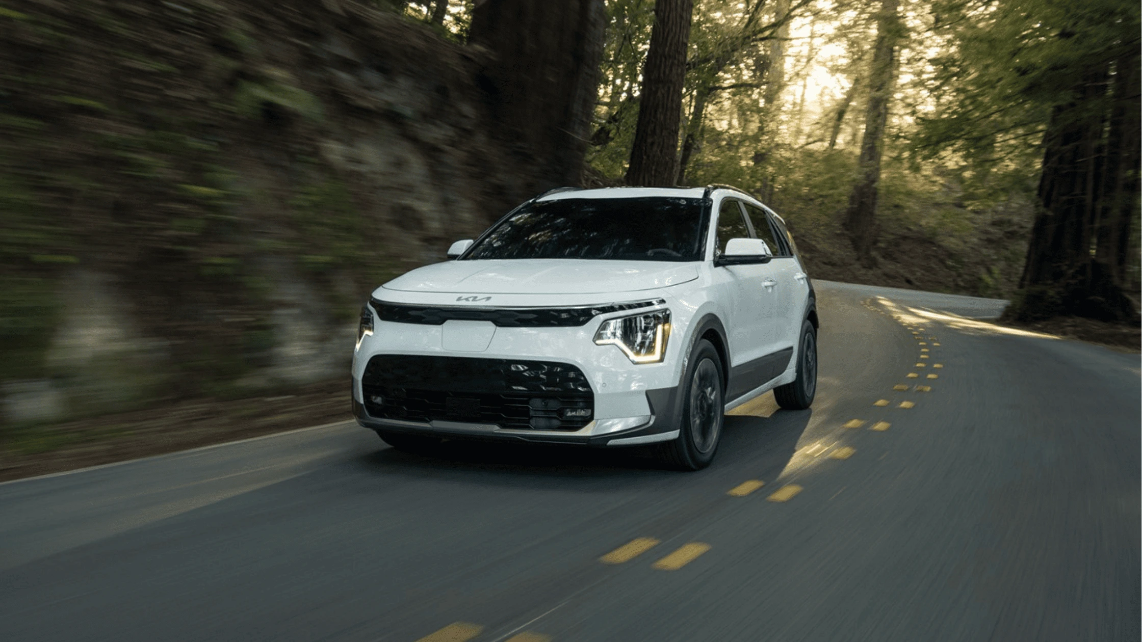 2025 Kia Niro EV in Fort Myers, FL 2025 Kia Niro EV white crossover driving along a winding road near Fort Myers, FL