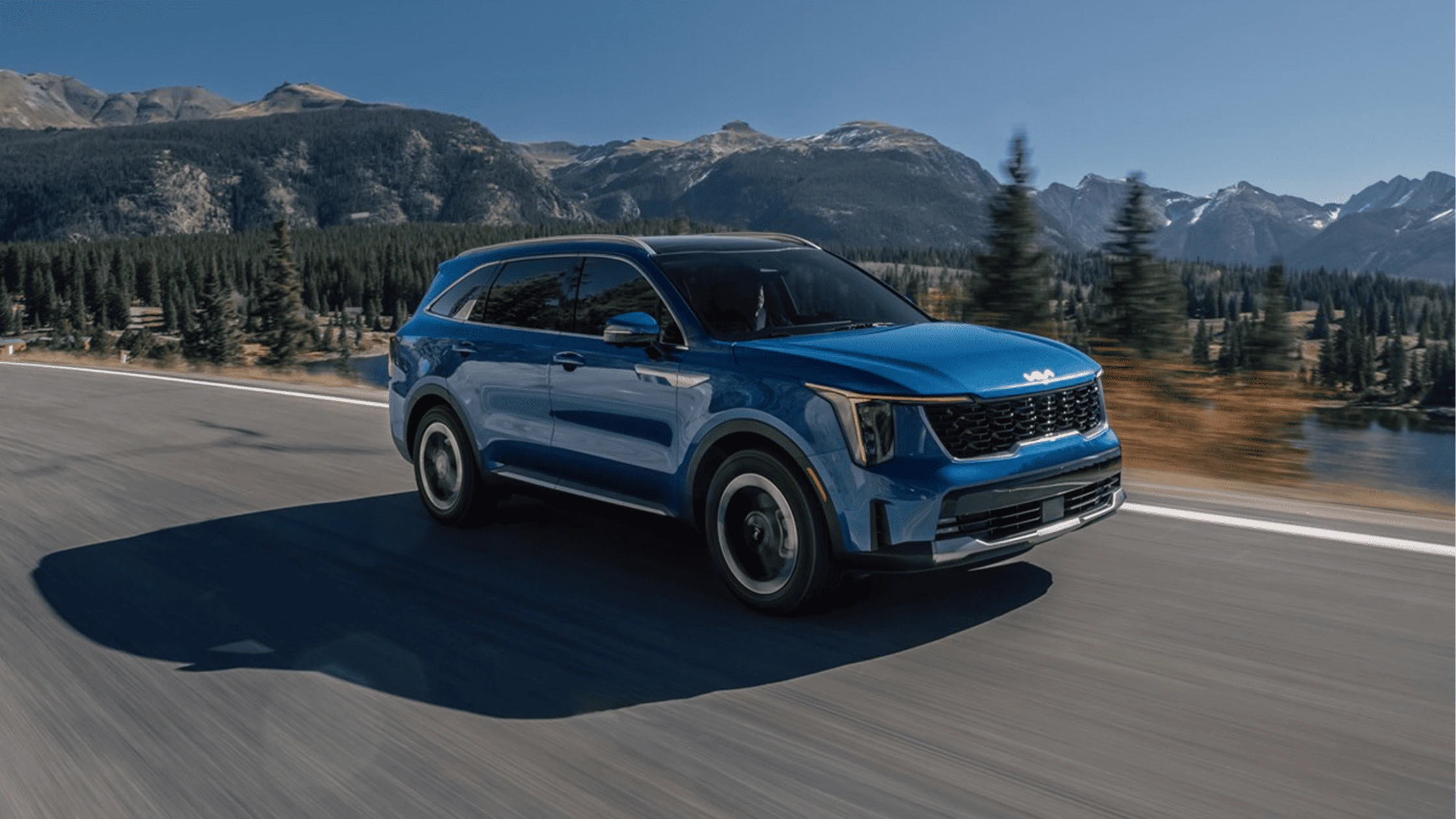 The 2025 Kia Sorento Hybrid in Fort Myers, FL A blue 2025 Kia Sorento Hybrid driving on a scenic mountain road, highlighting its sleek exterior and modern design.