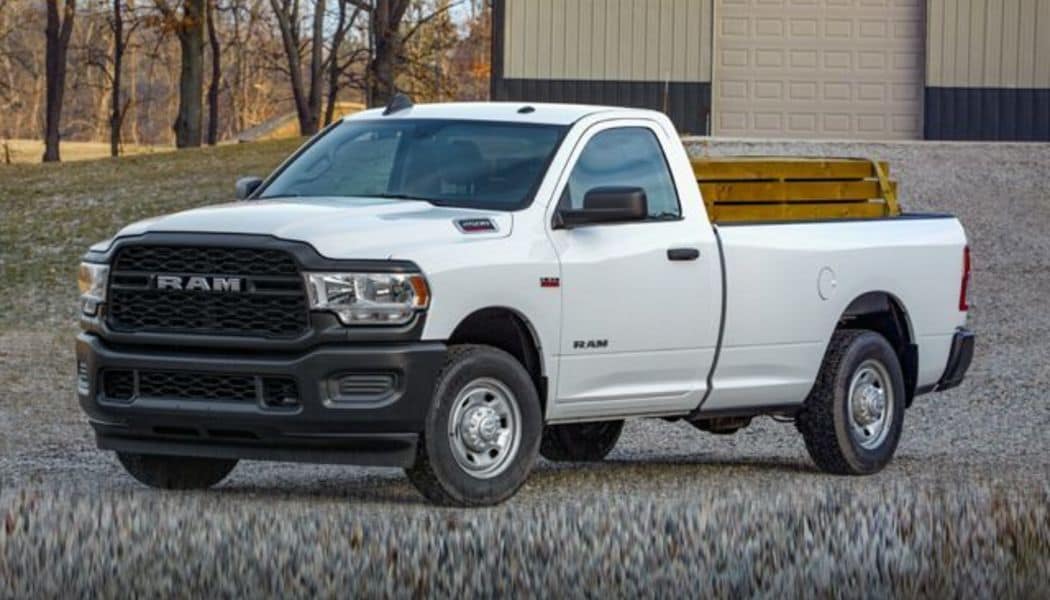 2020 Ram 2500 Truck Big Horn white parked in front of industrial garage and trees_res.jpg