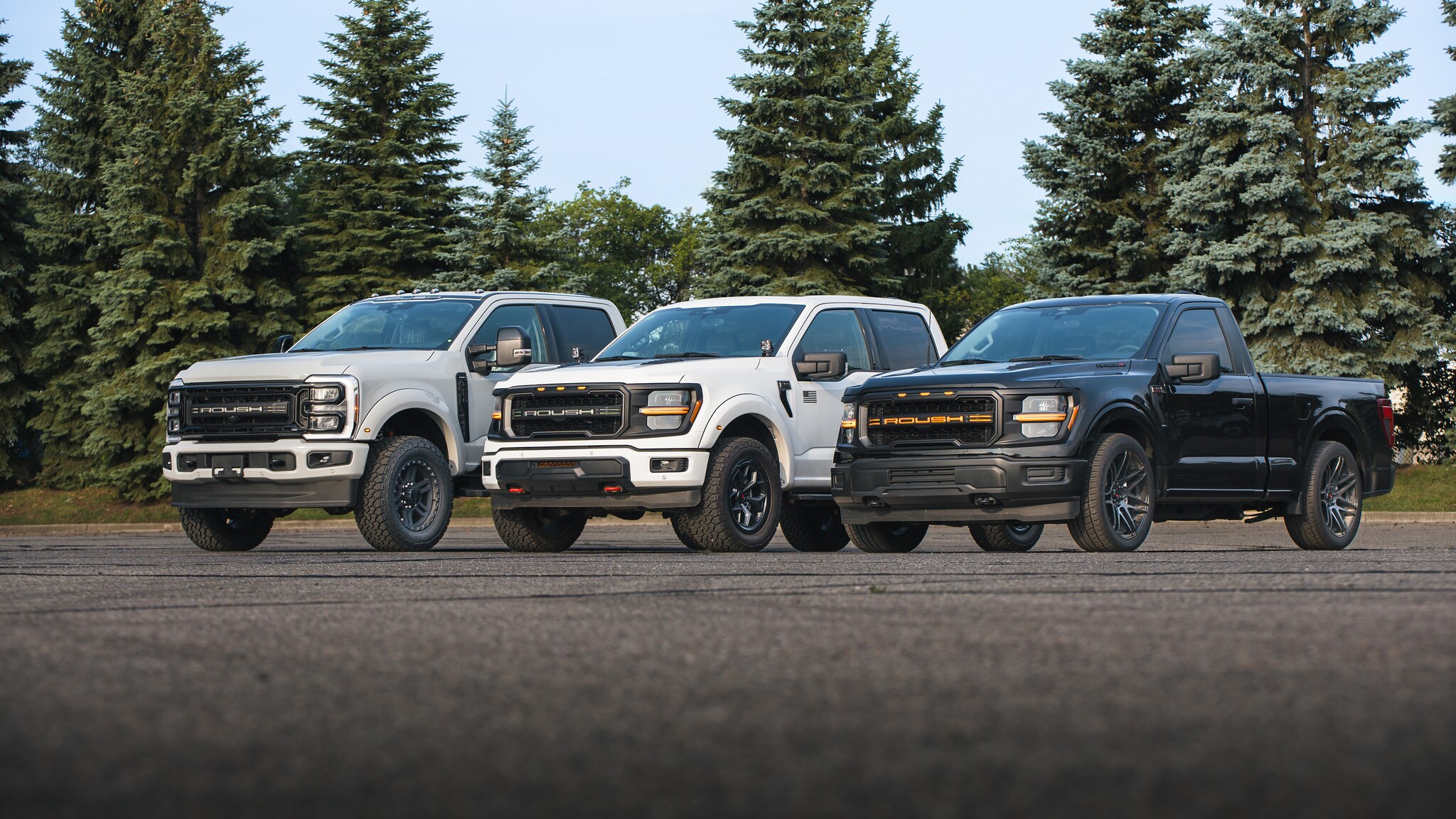 White ROUSH Super Duty, white ROUSH F-150 SuperCrew, and black ROUSH F-150 regular cab lined up together