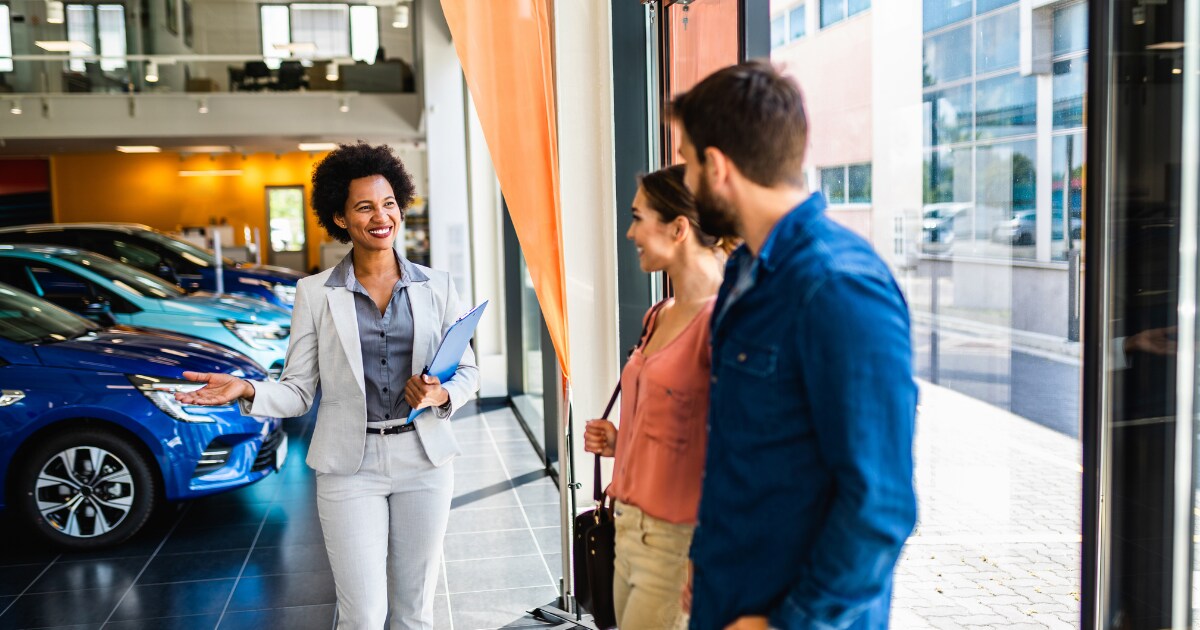 Young couple walking into a used Genesis showroom Young couple walking into a used Genesis showroom