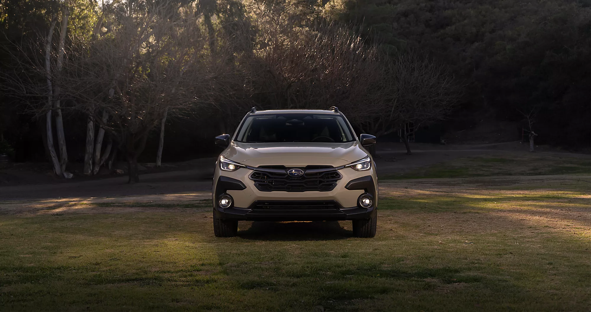 The front of a white 2026 Subaru Crosstrek Hybrid parked in the woods.
