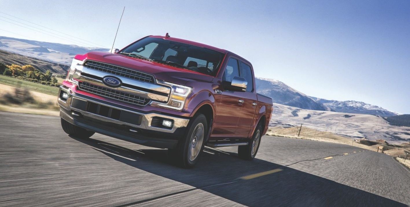 A red Ford F-150 driving on the road.