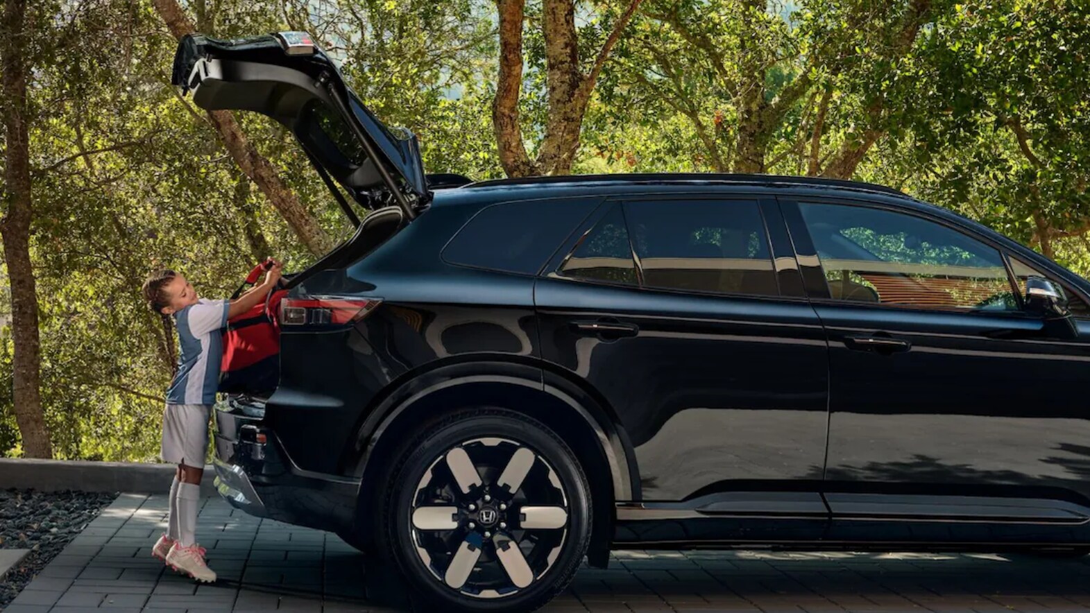 A young child loading the trunk of the Honda Prologue