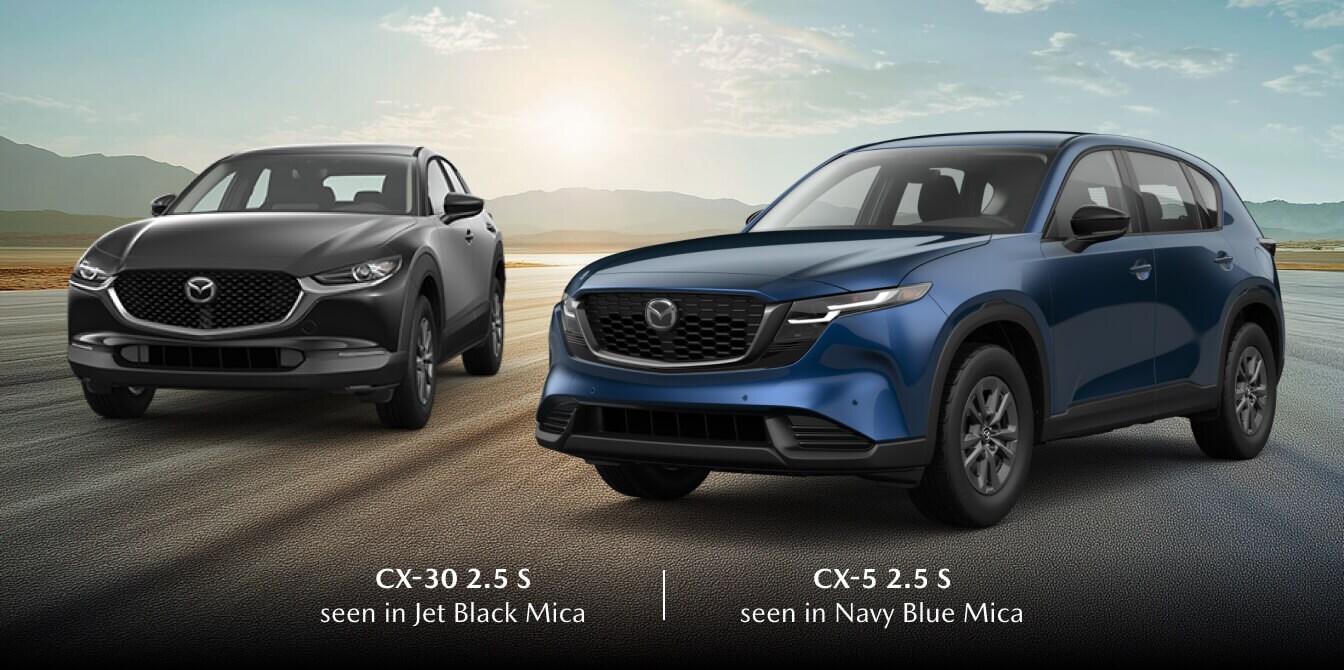 2026 Mazda CX-30 2.5 S in Jet Black Mica and CX-5 2.5 S in Navy Blue Mica, posed on an open road at sunrise.