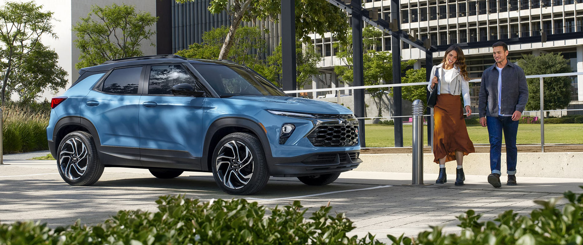 2026 Chevy Trailblazer Trim Comparison A couple walking towards a light blue 2026 Chevy Trailblazer.