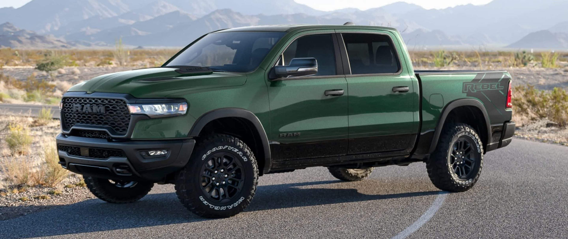 2026 RAM 1500 Trim Comparison A green 2026 RAM 1500 parked in the middle of the road on a turn in the desert.