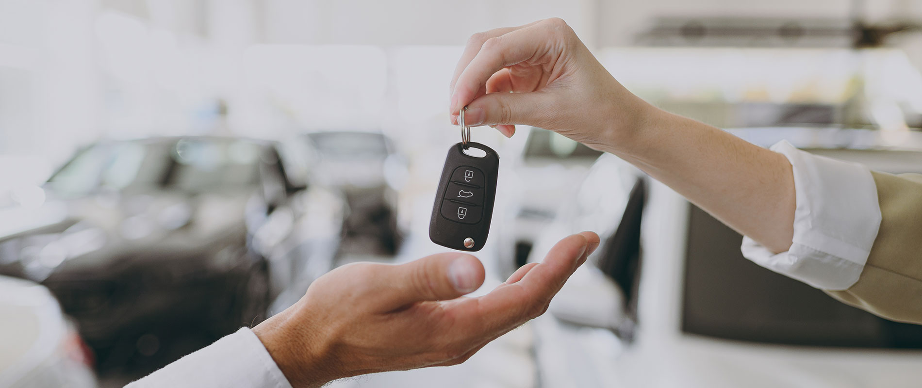 CDJR Dealership Near Milton, VT A car dealership salesperson handing the car keys over to a customer