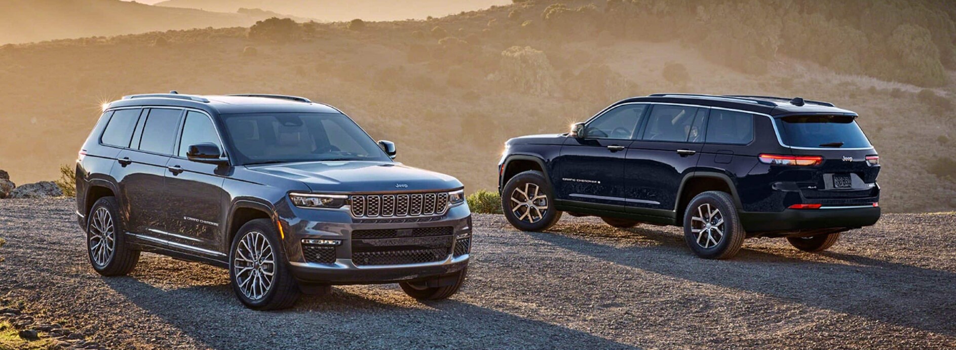 A pair of dark-colored Jeep Grand Cherokees parked on a dirt road over a cliff and facing opposite directions. A pair of dark-colored Jeep Grand Cherokees parked on a dirt road over a cliff and facing opposite directions.