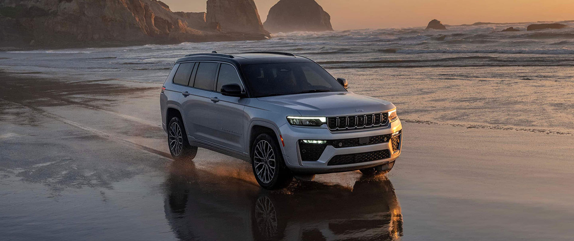 Jeep Grand Cherokee For Sale Near Colchester A silver Jeep Grand Cherokee driving across a beach by the water.