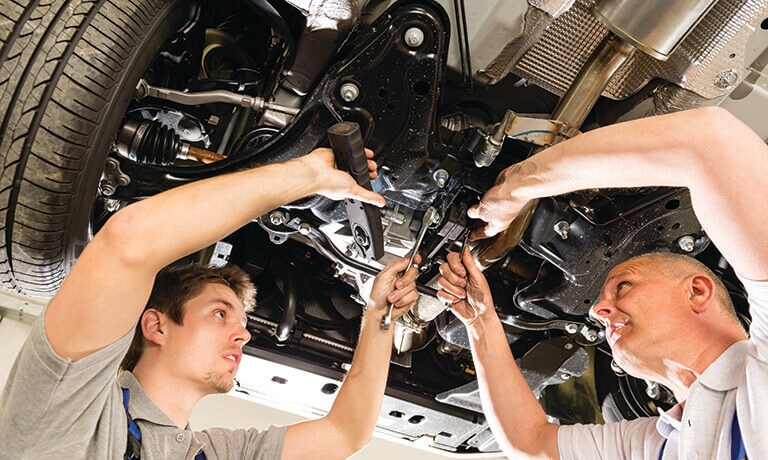 Two Mechanics Working Under Raised Car