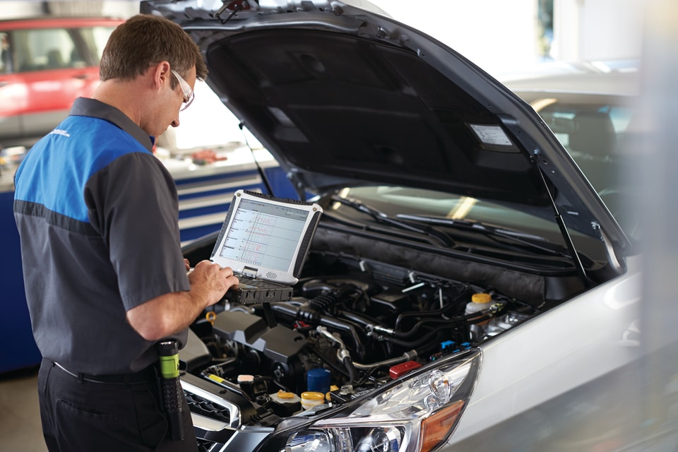 Subaru car service technician diagnosing car with hood up.jpg