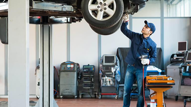Mechanic inspecting the undercarriage on a lifted vehicle