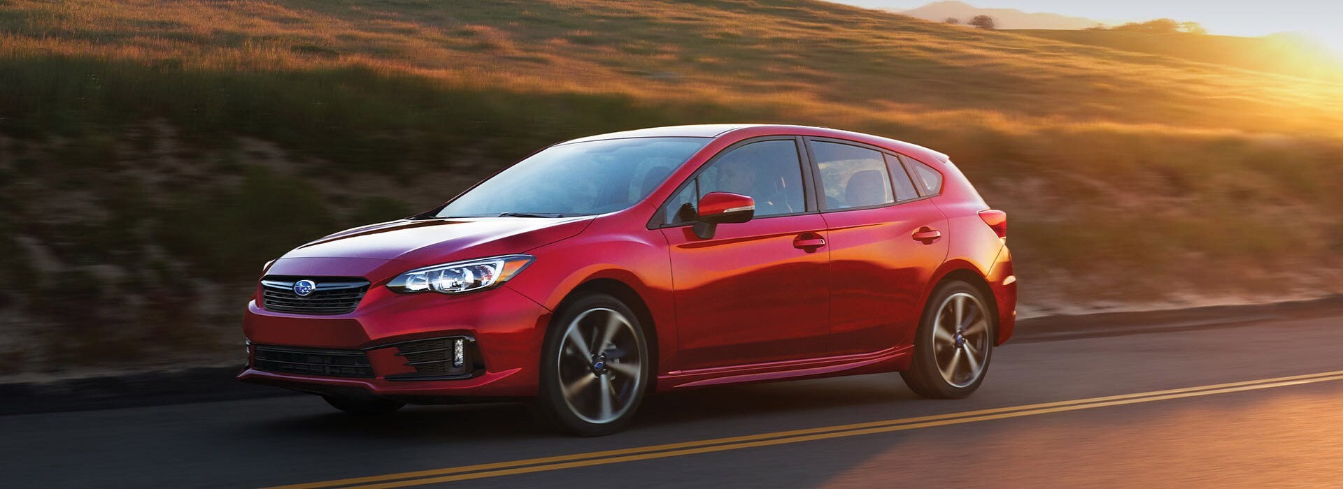 New-2022-Subaru-Impreza.jpg The sporty new 2022 Subaru Impreza in red driving doem the road at sunset.