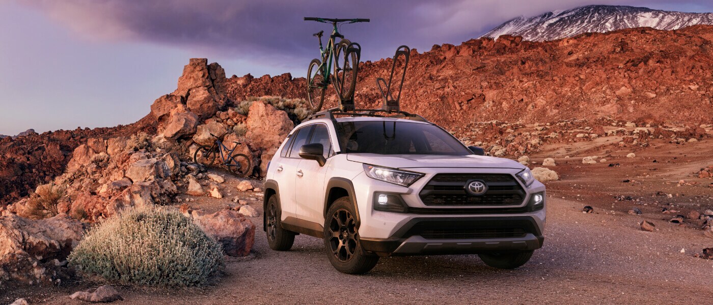 2020 Toyota RAV4 in white with bike racks parked in desert mountians off road during the day