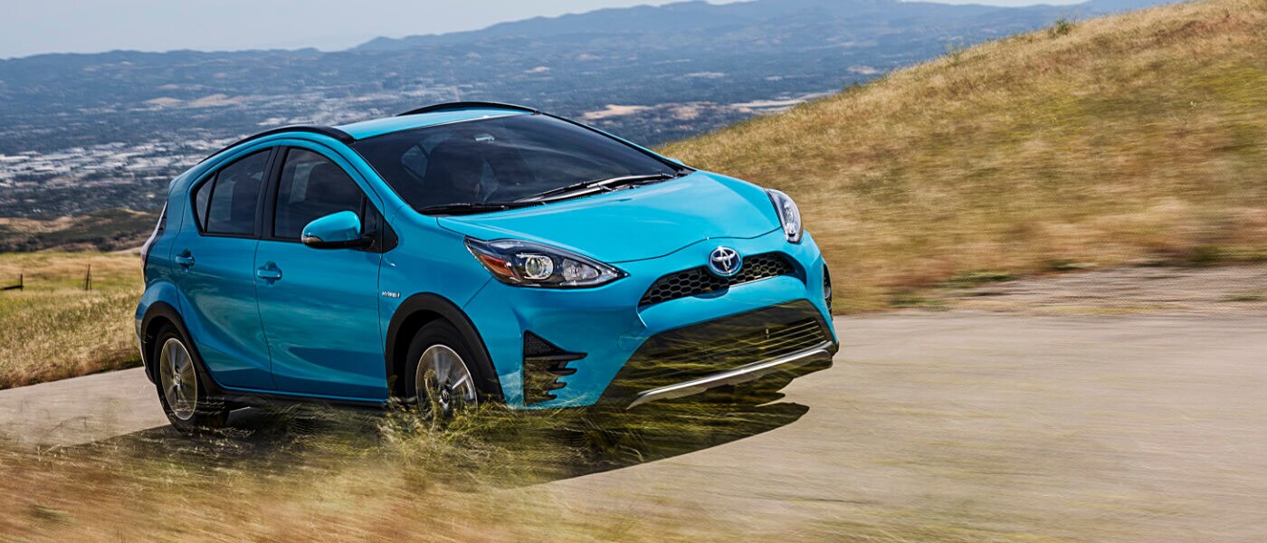 2019 Toyota Prius in blue driving on road up hill with seanic background
