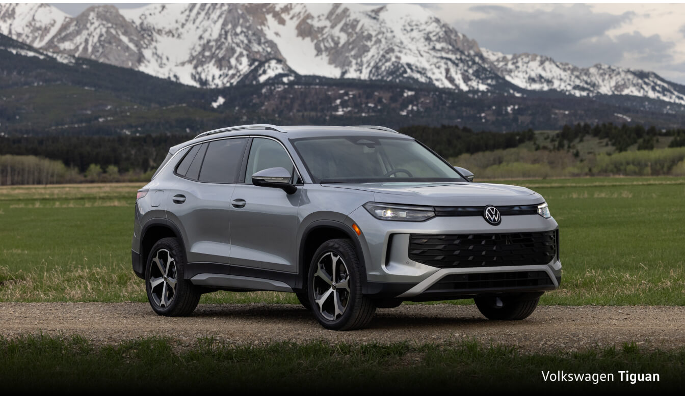 Volkswagan Tiguan in front of a field with mountains in the background.