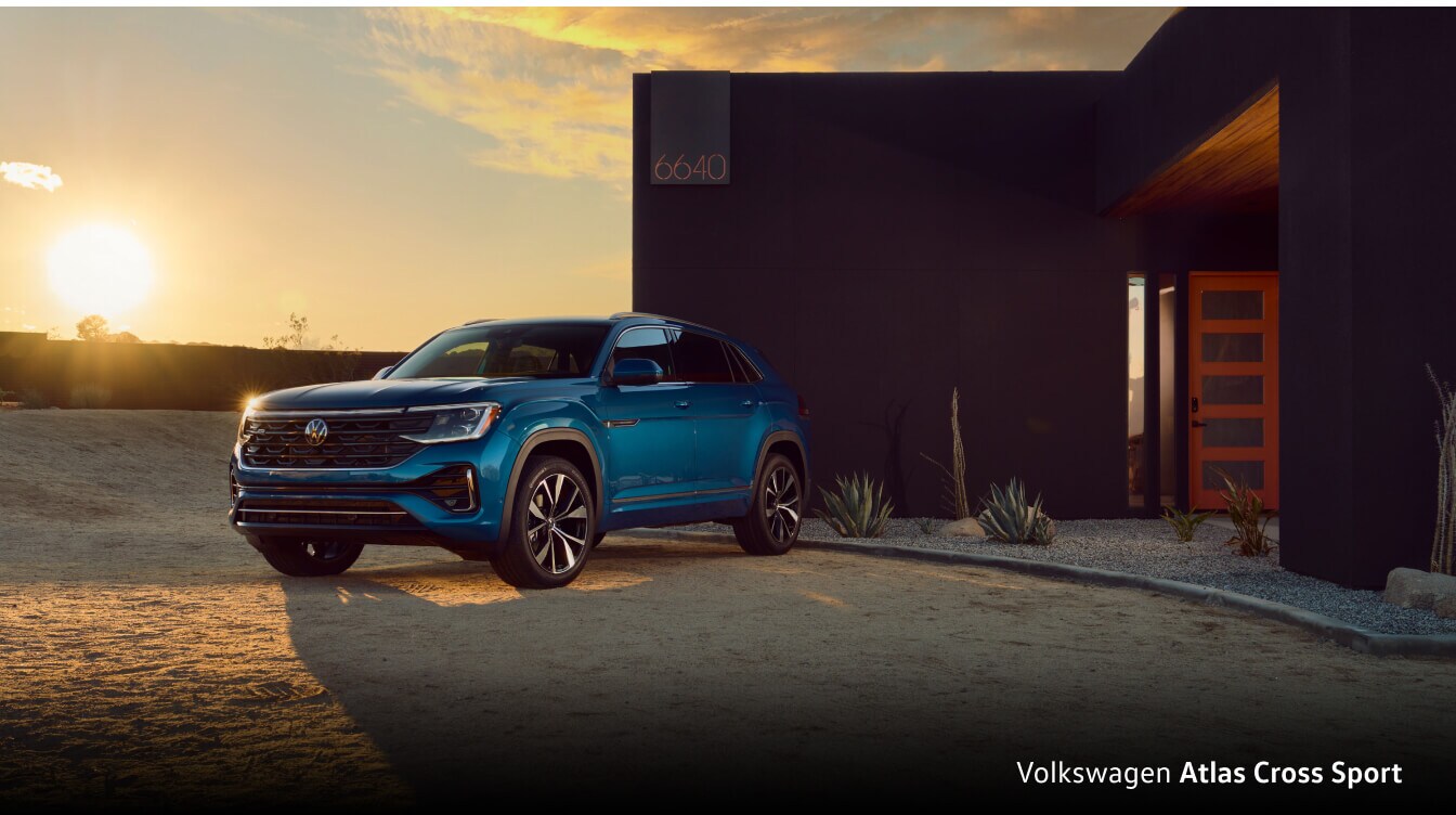Volkswagen Atlas Cross Sport parked in front of modern domicile located in a desert setting during the sunset.