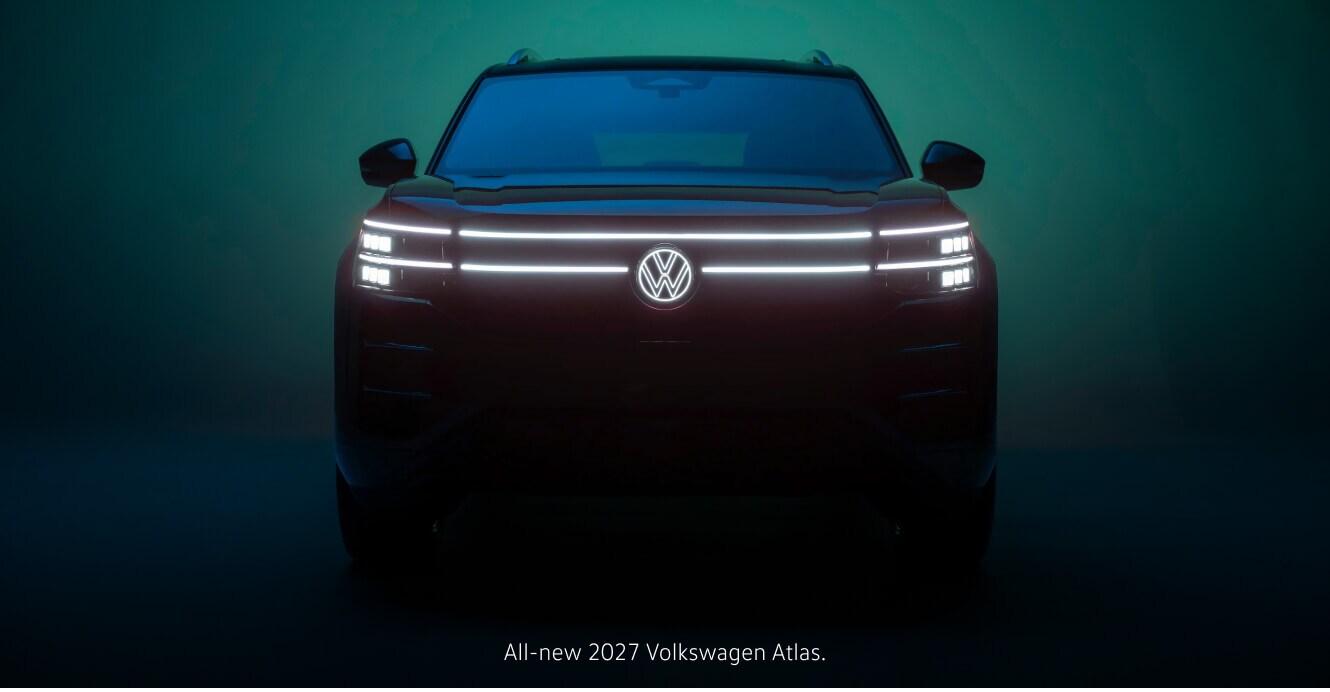 Front view of an illuminated 2027 Volkswagen Atlas showcasing its light bar against a glowing backdrop.