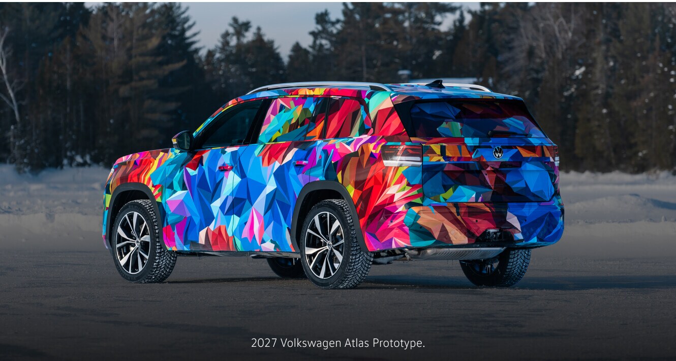 Three-quarter rear view of a 2027 Volkswagen Atlas Prototype driving over a snow field.