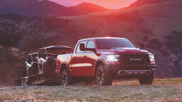 Ram 1500 A red Ram 1500 towing ATVs throught the mountains at sunset