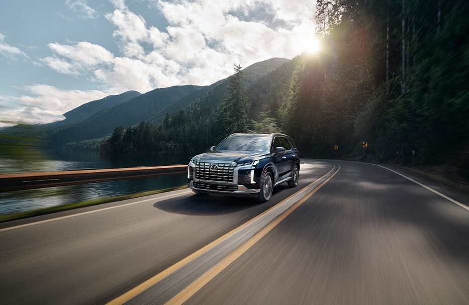 All-New 2023 Hyundai Palisade at Haddad Hyundai | Front profile of a 2023 Hyundai Palisade driving down the road