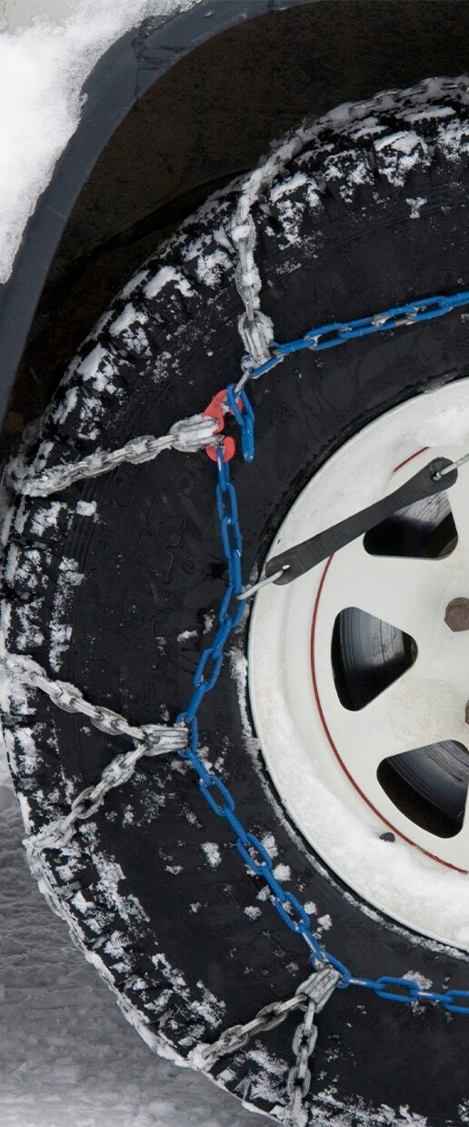 Accessories that help keep your Hyundai protected at Haddad Hyundai in Pittsfield, MA | Close up of tire chains attached to tire to help the car have better traction with snow