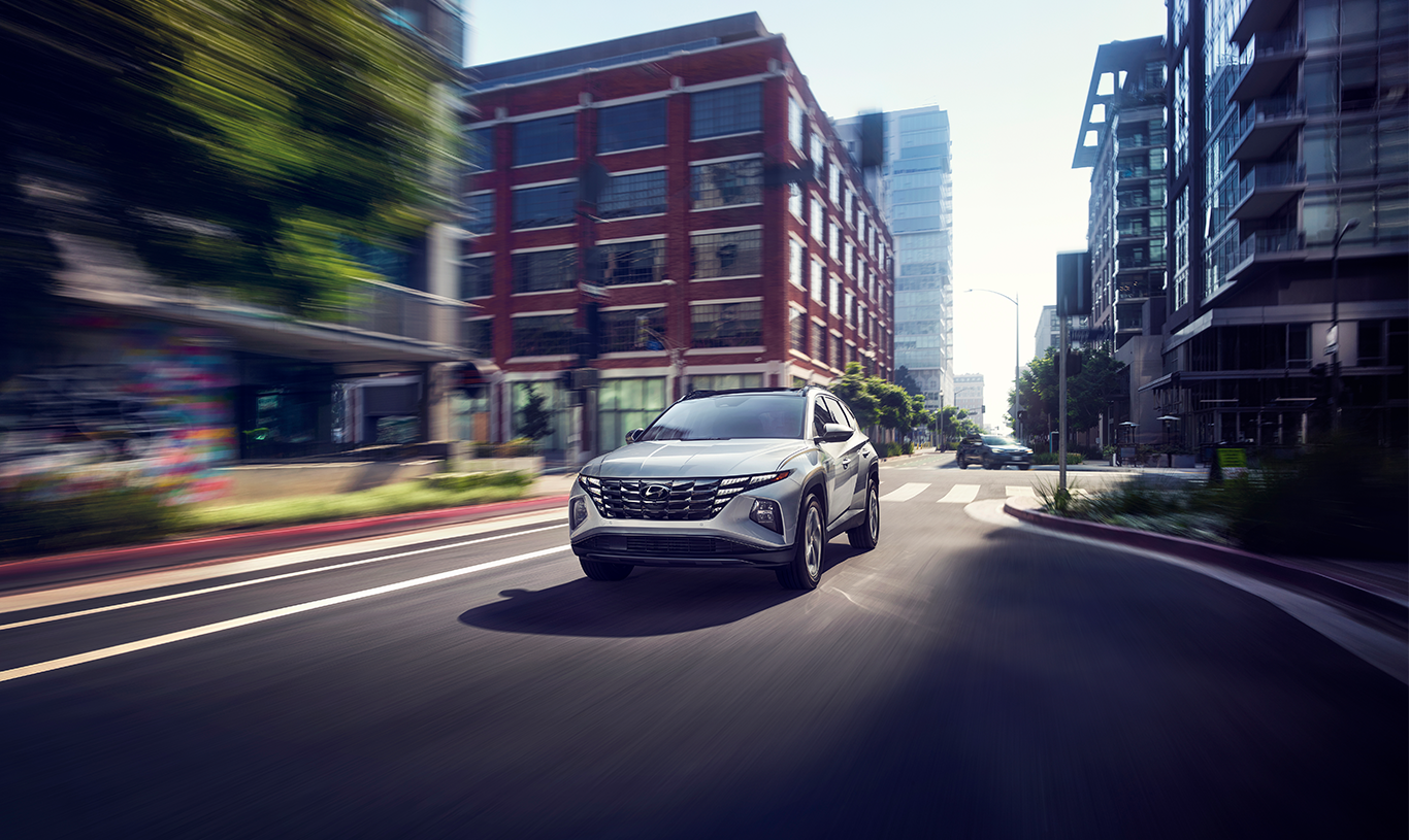 2023 Hyundai Santa Fe at Haddad Hyundai | Front profile of a white 2023 Hyundai Santa Fe driving over a small puddle with views of the mountains in the background